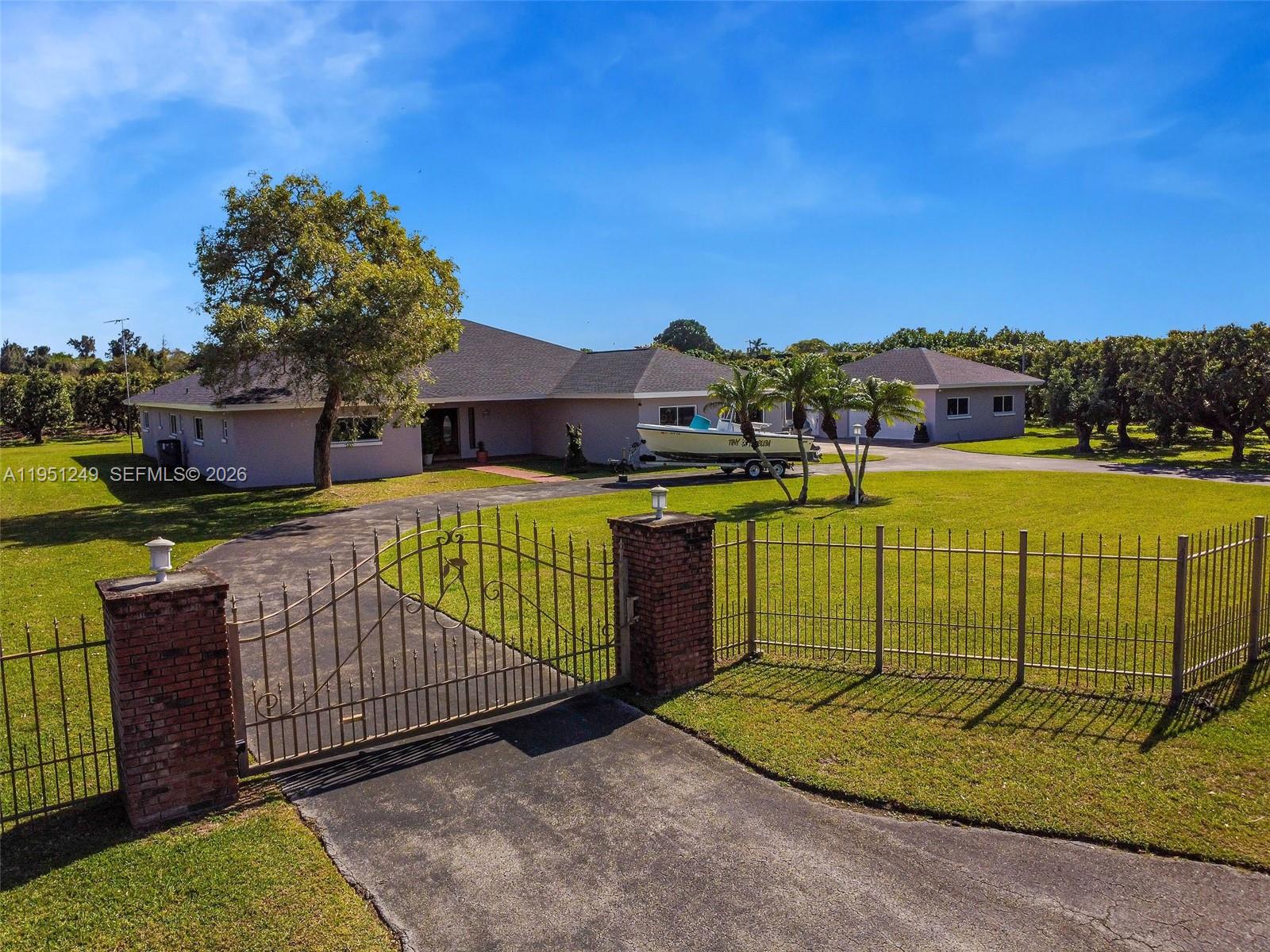 A gated driveway leads to a single-story house with a boat parked in front — 23505 SW 153rd Ave, Homestead FL 33032, HOMESTEAD, FL
