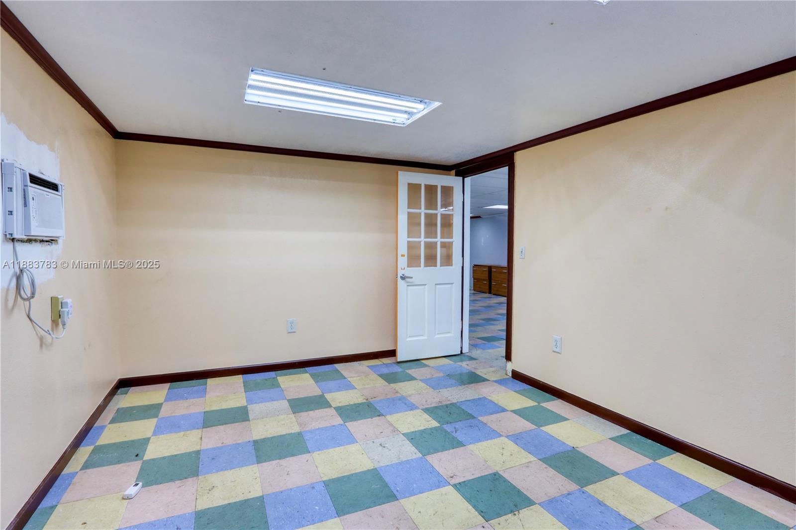 An empty room features yellow walls, dark trim, and a multicolored checkered tile floor — 6250 W 21st Ct, Hialeah FL 33016, HIALEAH, FL