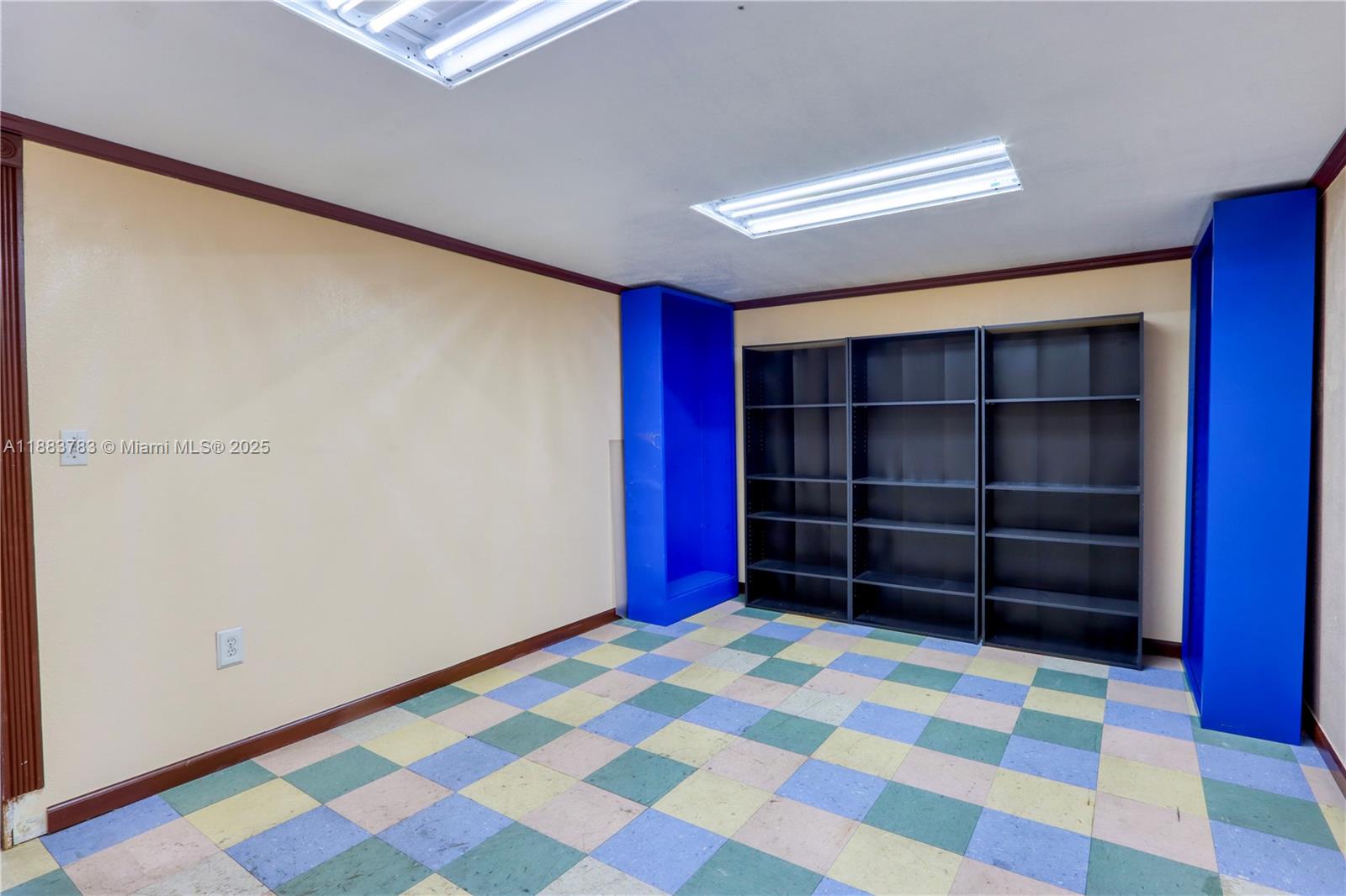 A room with checkered floor tiles, beige walls, blue accents, and three black bookshelves — 6250 W 21st Ct, Hialeah FL 33016, HIALEAH, FL