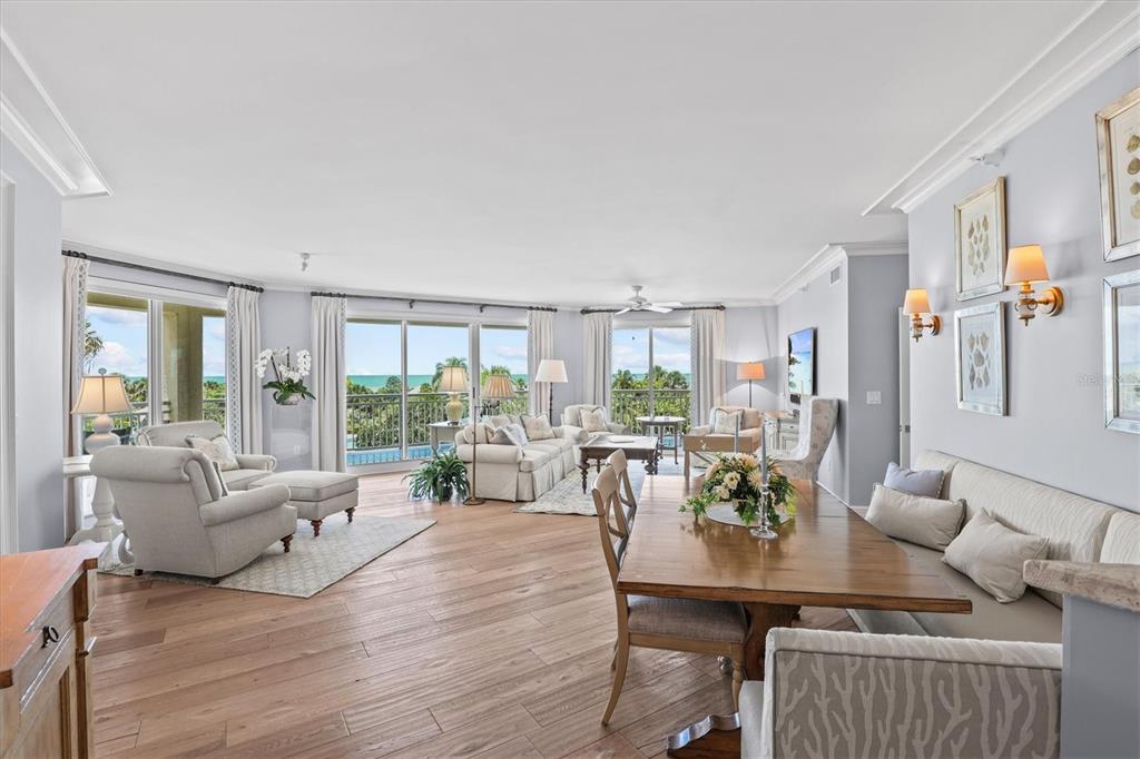 A bright, open-concept living and dining area features hardwood floors and floor-to-ceiling windows with ocean views — 1170 GULF BOULEVARD UNIT 201, CLEARWATER BEACH, FL