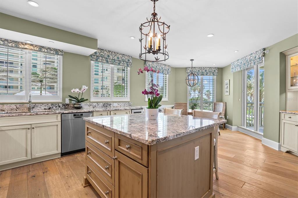 A kitchen featuring a granite-topped island, light-colored cabinetry, and large windows with patterned valances — 1170 GULF BOULEVARD UNIT 201, CLEARWATER BEACH, FL
