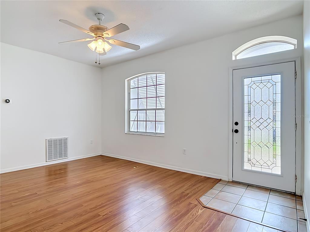 An empty room with wood flooring, a ceiling fan, a window, and a front door — 4624 S ATLANTIC AVENUE, NEW SMYRNA BEACH, FL