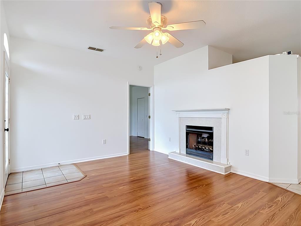 A living room features wood-look flooring, a white fireplace, and a ceiling fan — 4624 S ATLANTIC AVENUE, NEW SMYRNA BEACH, FL