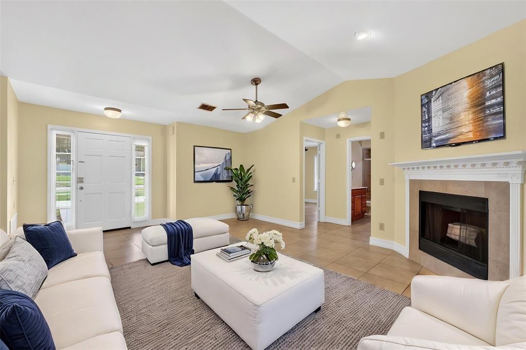 A living room features a fireplace, white furniture, tile floors, and a vaulted ceiling — 3633 JERICHO DRIVE, CASSELBERRY, FL