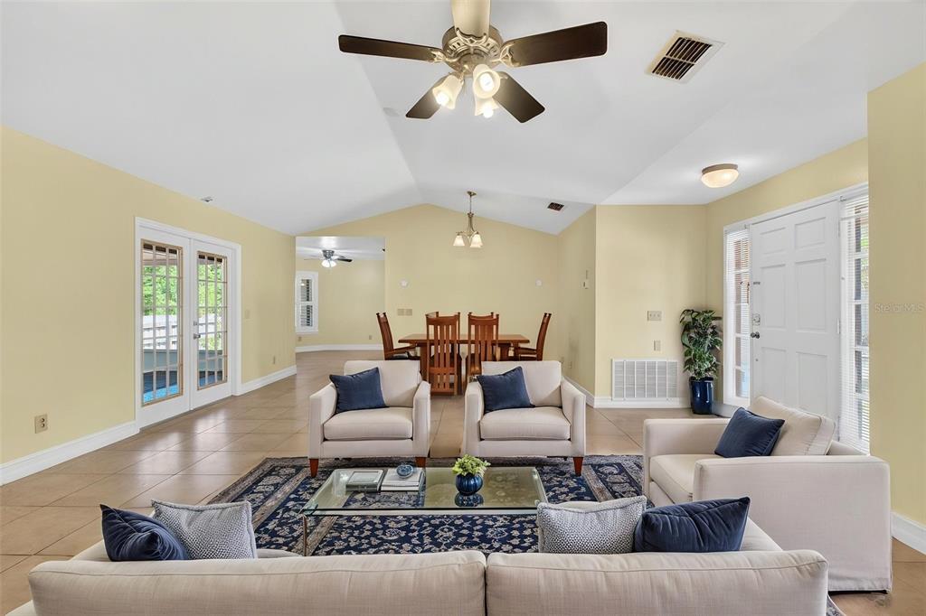 A living room with beige walls, tile floors, and a dining area in the background — 3633 JERICHO DRIVE, CASSELBERRY, FL