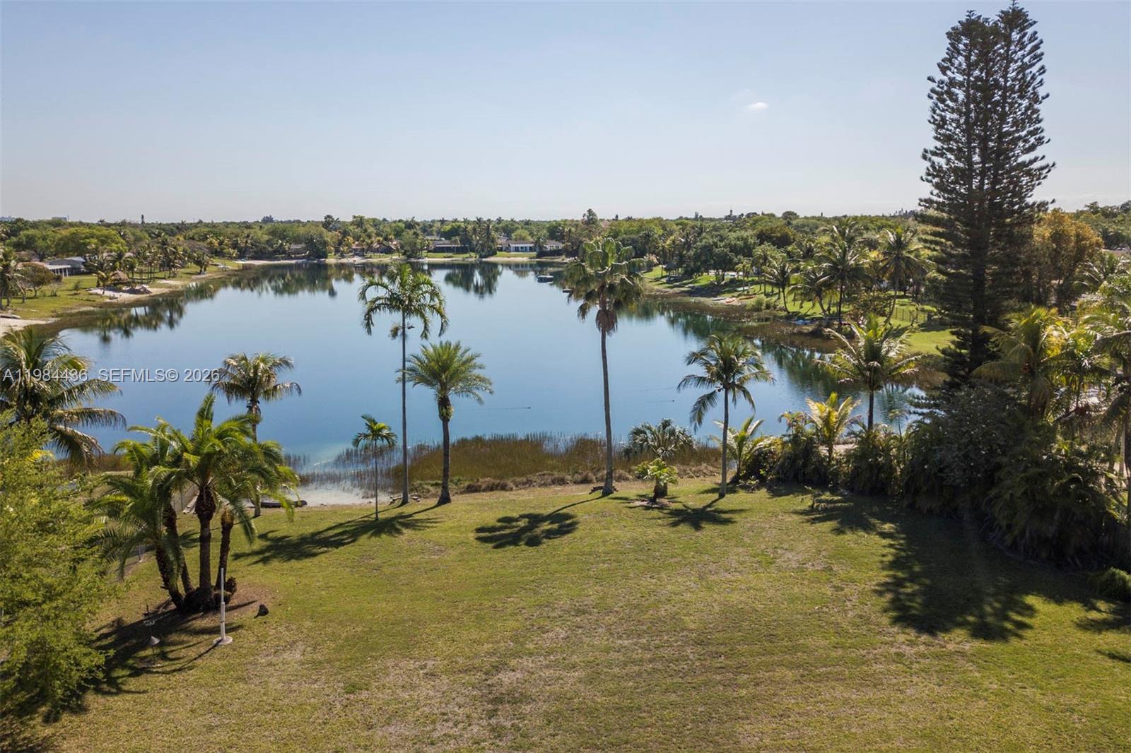 An aerial view shows a grassy yard leading to a lake surrounded by palm trees — 11807 SW 112th Ave, Miami FL 33176, MIAMI, FL