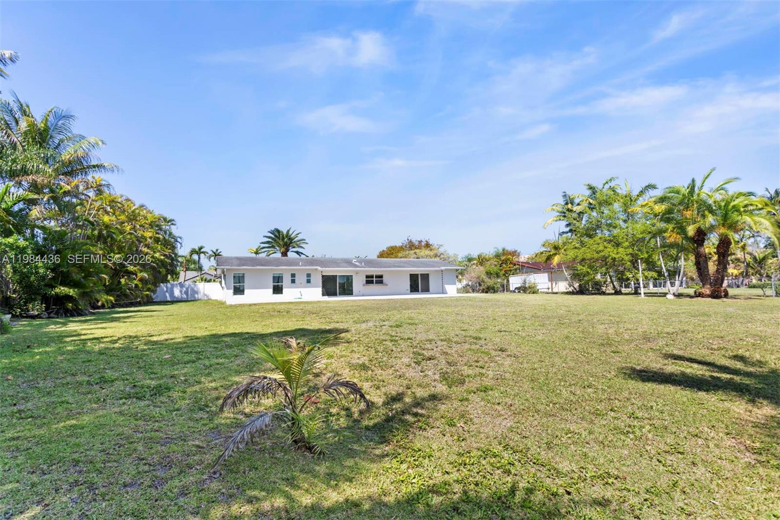 The exterior of a white, single-story house sits on a large, grassy backyard lot — 11807 SW 112th Ave, Miami FL 33176, MIAMI, FL