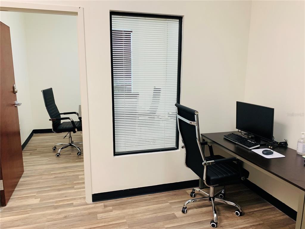 An office space features a desk with a computer, two chairs, and a window — 7065 WESTPOINTE BOULEVARD UNIT 320, ORLANDO, FL