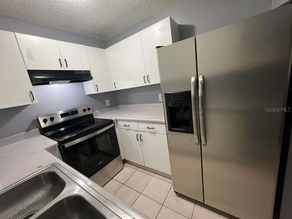 A kitchen features white cabinets, stainless steel appliances, light countertops, and tile flooring — 8301 N ALASKA STREET, TAMPA, FL