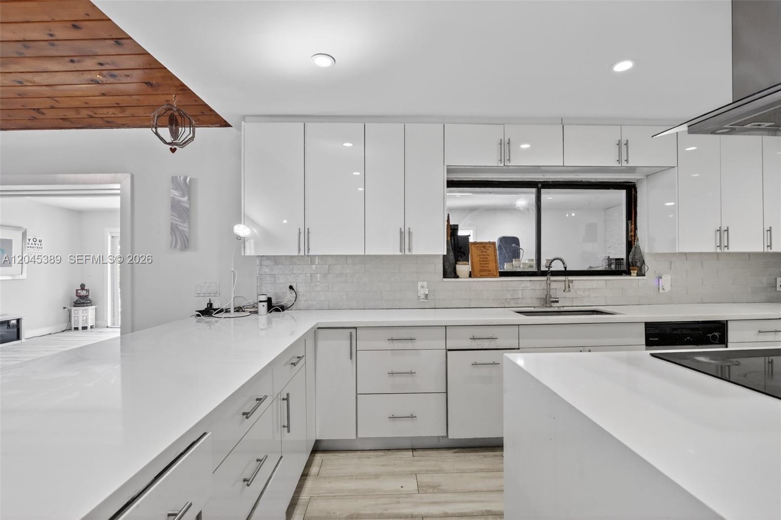 A modern kitchen features white glossy cabinets, white countertops, and a subway tile backsplash — 14401 SW 23rd St, Davie FL 33325, DAVIE, FL