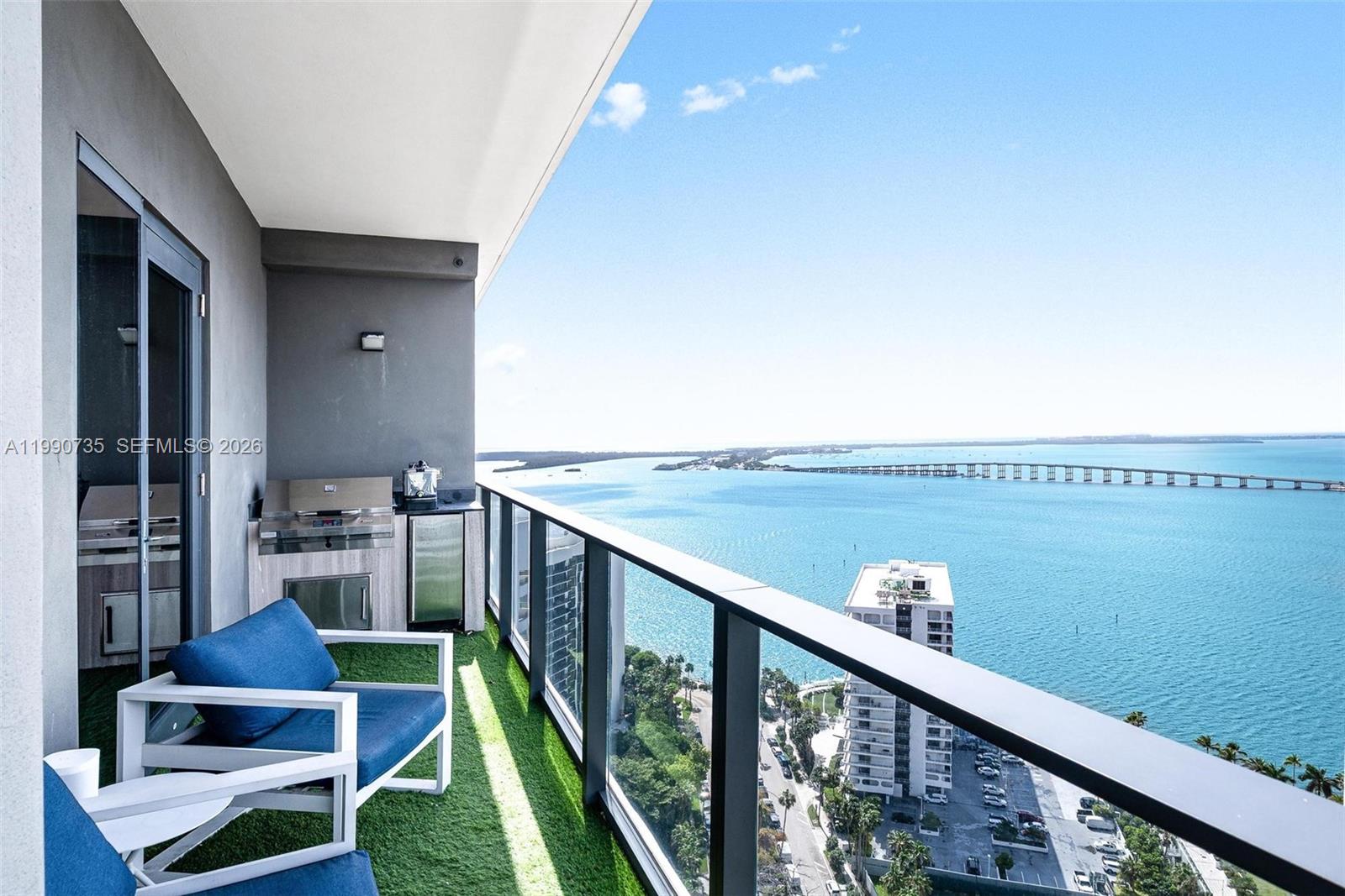 A high-rise balcony features artificial turf, outdoor kitchen appliances, and a panoramic bay view — 1451 Brickell Ave # 2704, Miami FL 33131, MIAMI, FL