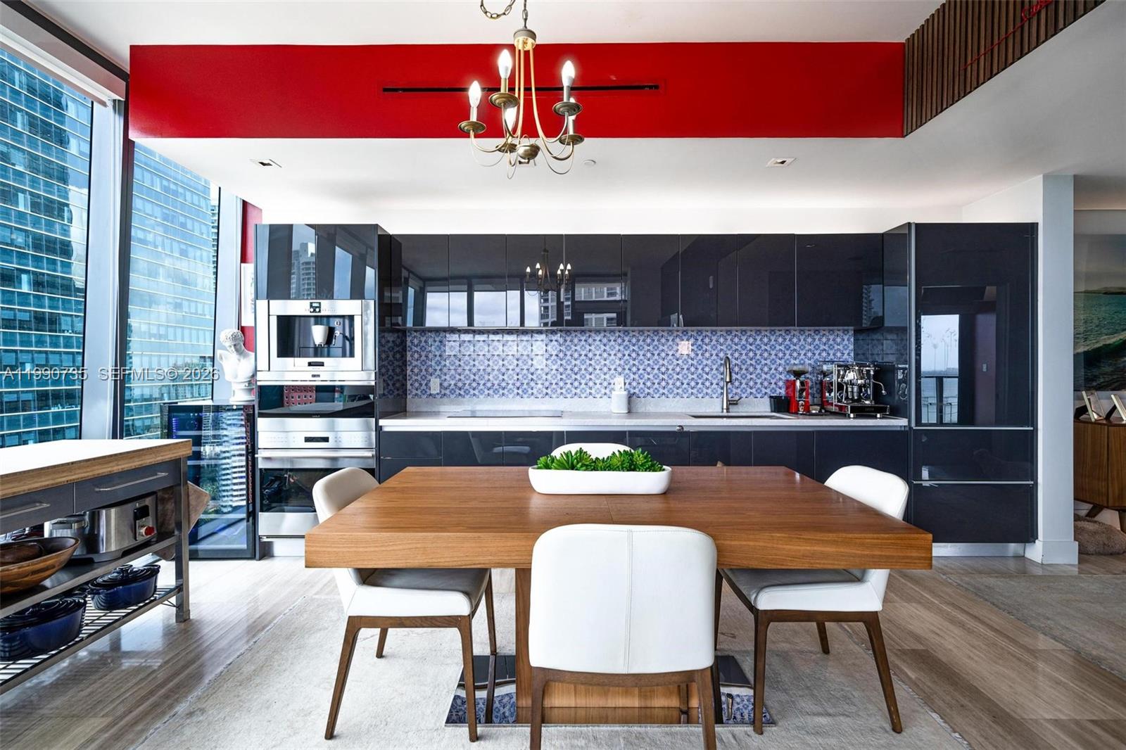 A modern kitchen features dark glossy cabinets, a blue patterned backsplash, and a wooden dining table — 1451 Brickell Ave # 2704, Miami FL 33131, MIAMI, FL