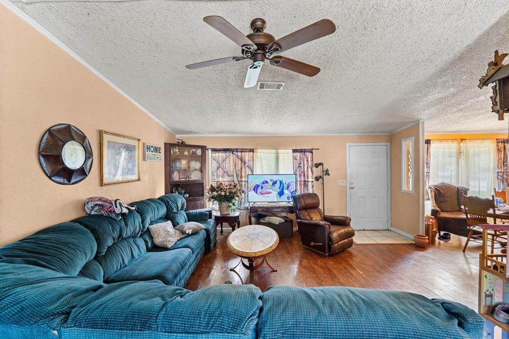 A living room features a blue sectional sofa, a ceiling fan, and hardwood flooring — 16143 PALACKY STREET, BROOKSVILLE, FL