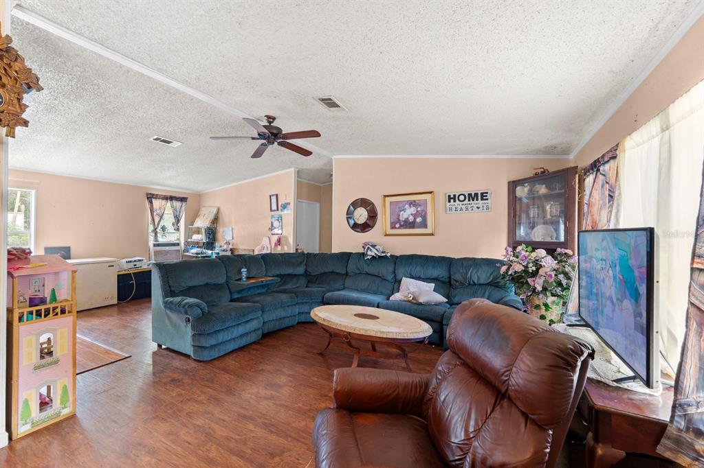 A living room features a large blue sectional, a brown recliner, and wood-look flooring — 16143 PALACKY STREET, BROOKSVILLE, FL