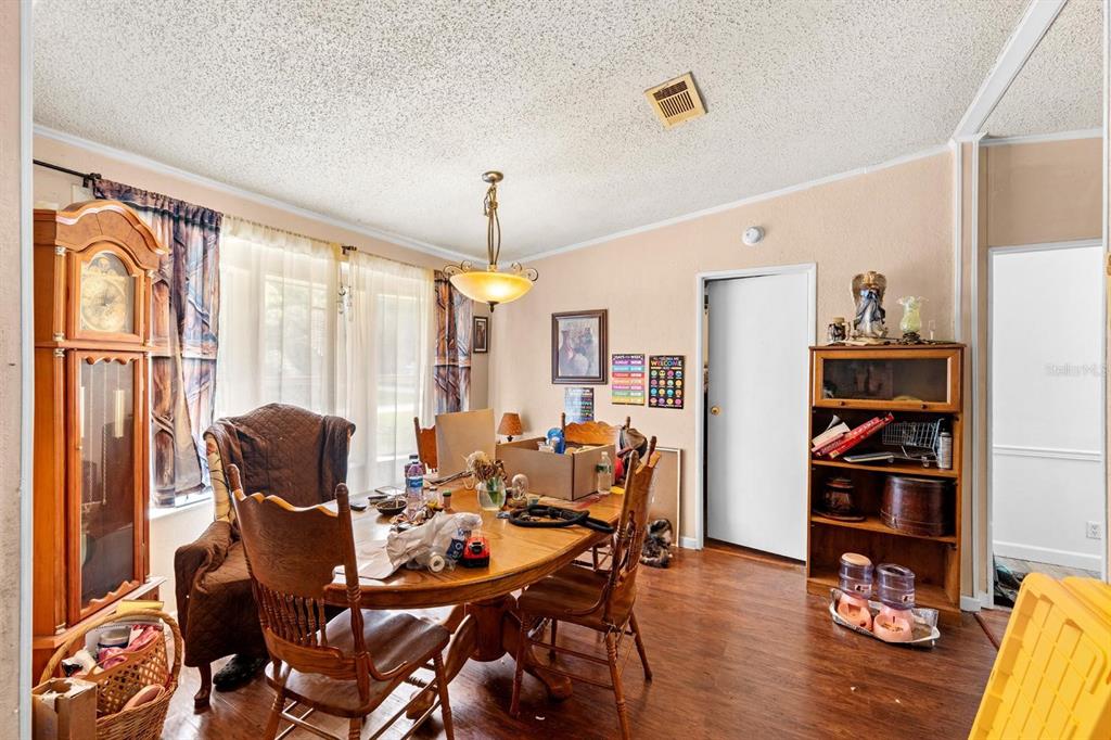 A dining room features a wooden table, chairs, a grandfather clock, and a wooden bookshelf — 16143 PALACKY STREET, BROOKSVILLE, FL
