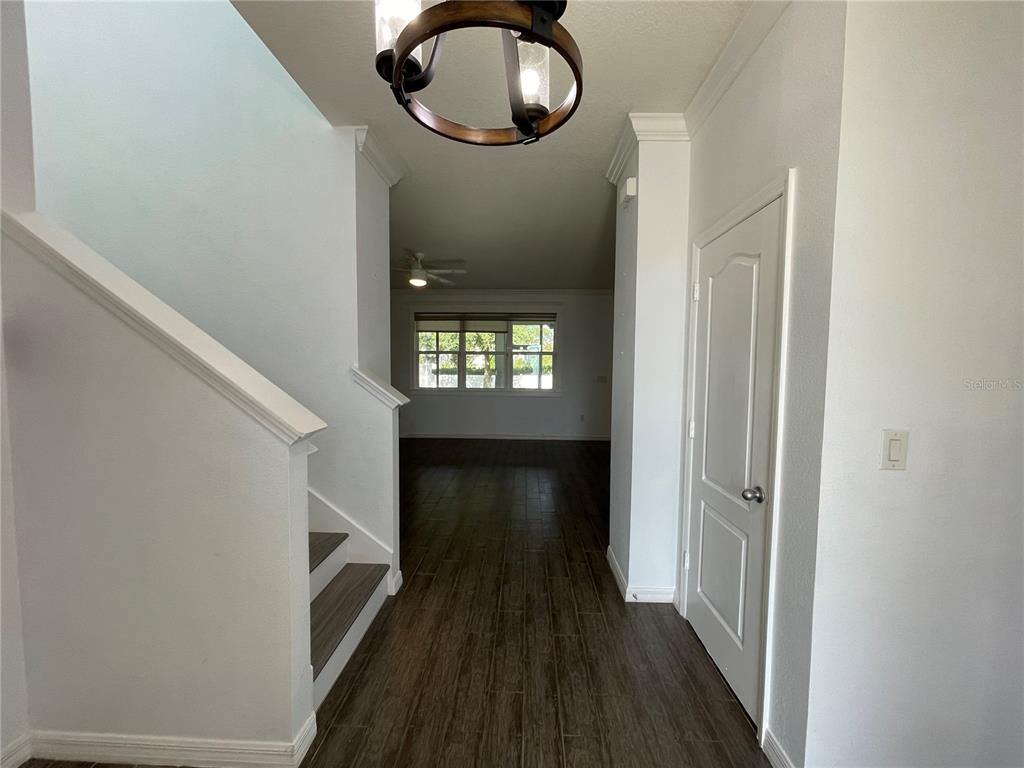 An entryway features a staircase, wood-look tile flooring, a light fixture, and a closed door — 4501 BALER TRAILS DRIVE, ST CLOUD, FL