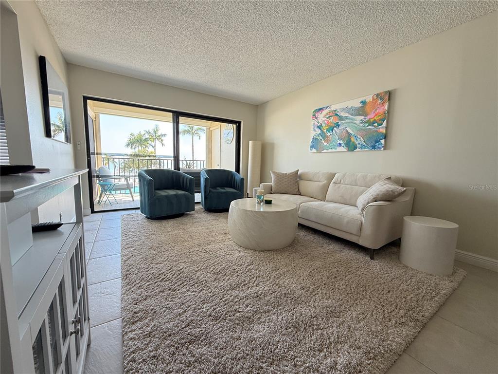 A living room features a white sofa, two blue armchairs, and a sliding glass door — 6322 PALMA DEL MAR BOULEVARD S UNIT 213, ST PETERSBURG, FL