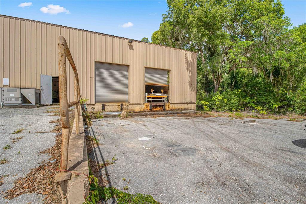 An exterior view of a metal warehouse building with two loading dock doors and pavement — 1031 NE 16TH STREET, OCALA, FL