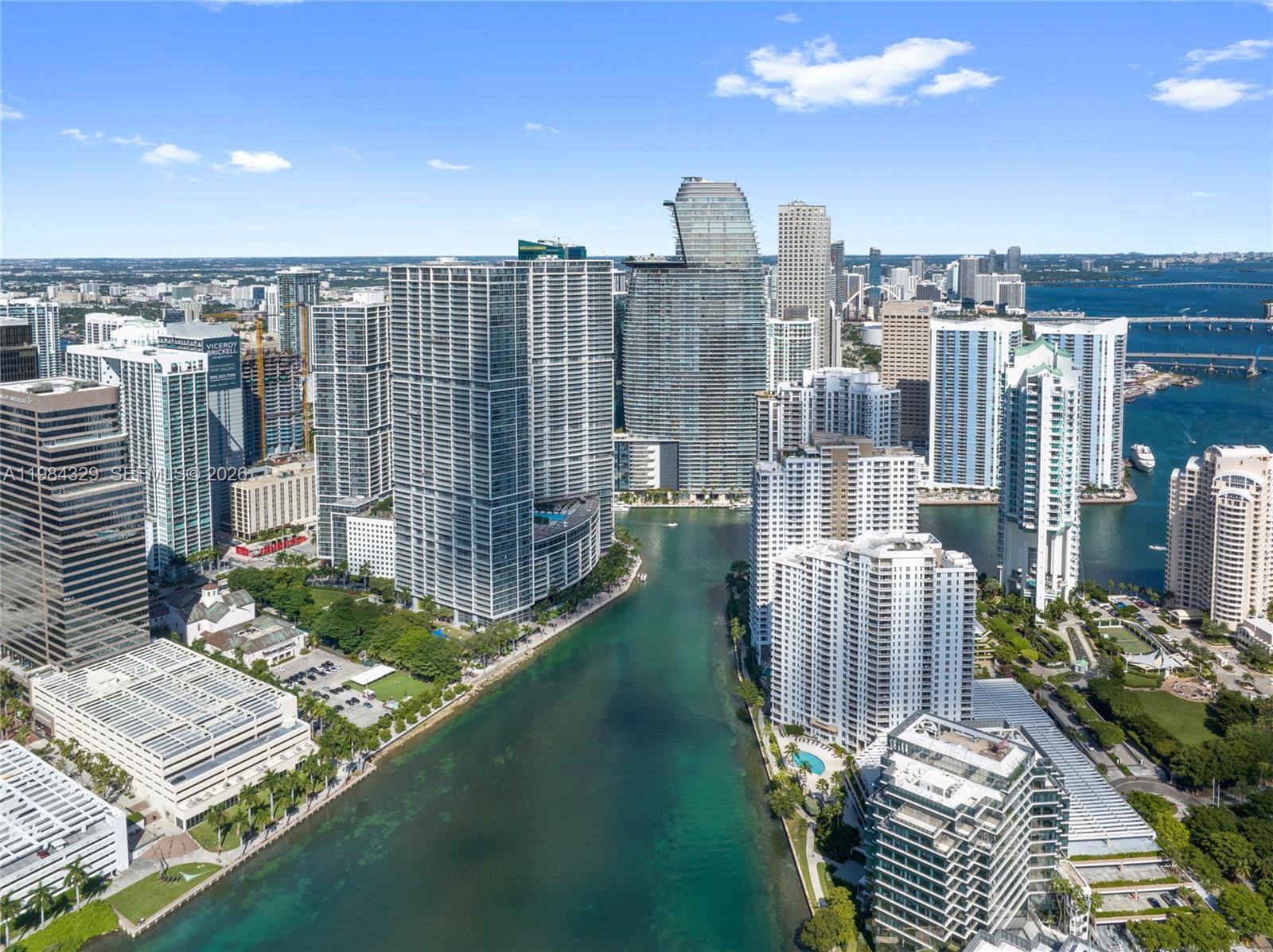 An aerial view shows high-rise buildings along a river in a dense urban city — 300 Biscayne Boulevard Way # 2601E, Miami FL 33131, MIAMI, FL