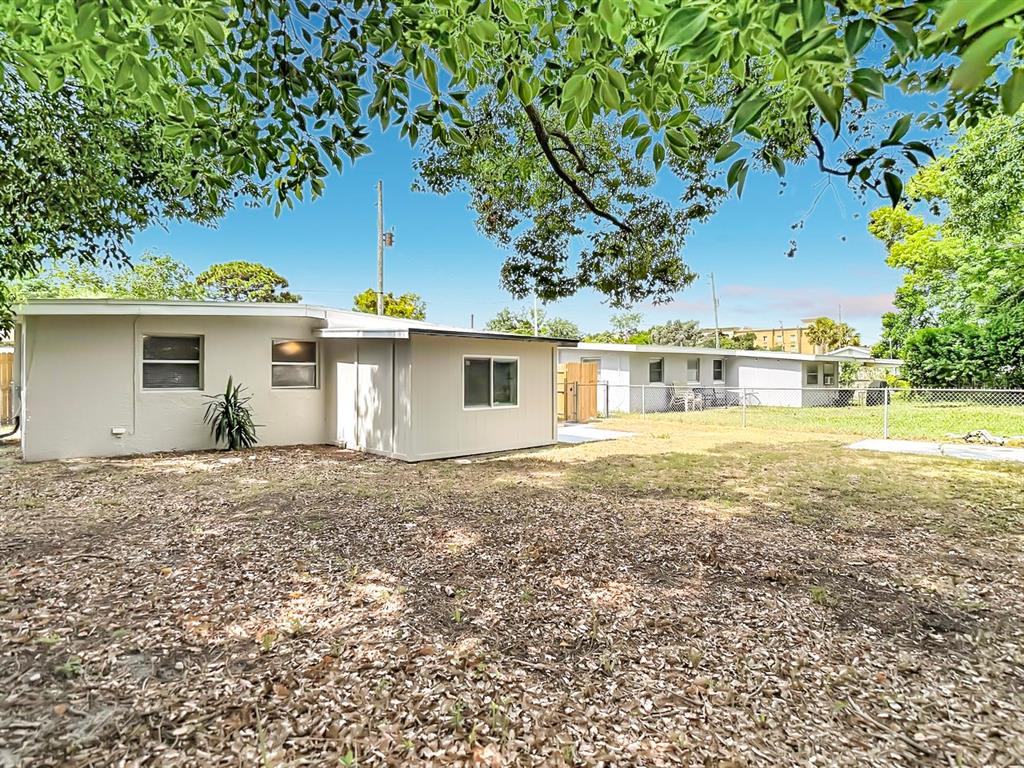 A beige single-story house exterior with a fenced backyard and scattered fallen leaves — 7133 ABIGAIL DRIVE, PORT RICHEY, FL