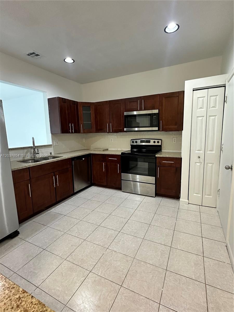 A kitchen features dark wood cabinets, stainless steel appliances, granite countertops, and light tile flooring — 5541 NW 90th Ter # 5541, Sunrise FL 33351, SUNRISE, FL