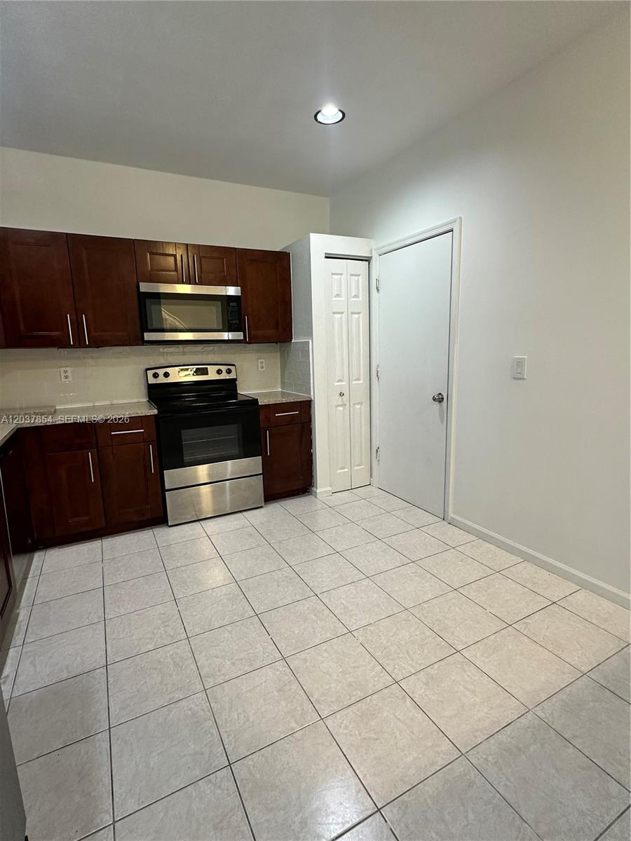 A kitchen features dark wood cabinets, stainless steel appliances, and light-colored floor tiles — 5541 NW 90th Ter # 5541, Sunrise FL 33351, SUNRISE, FL