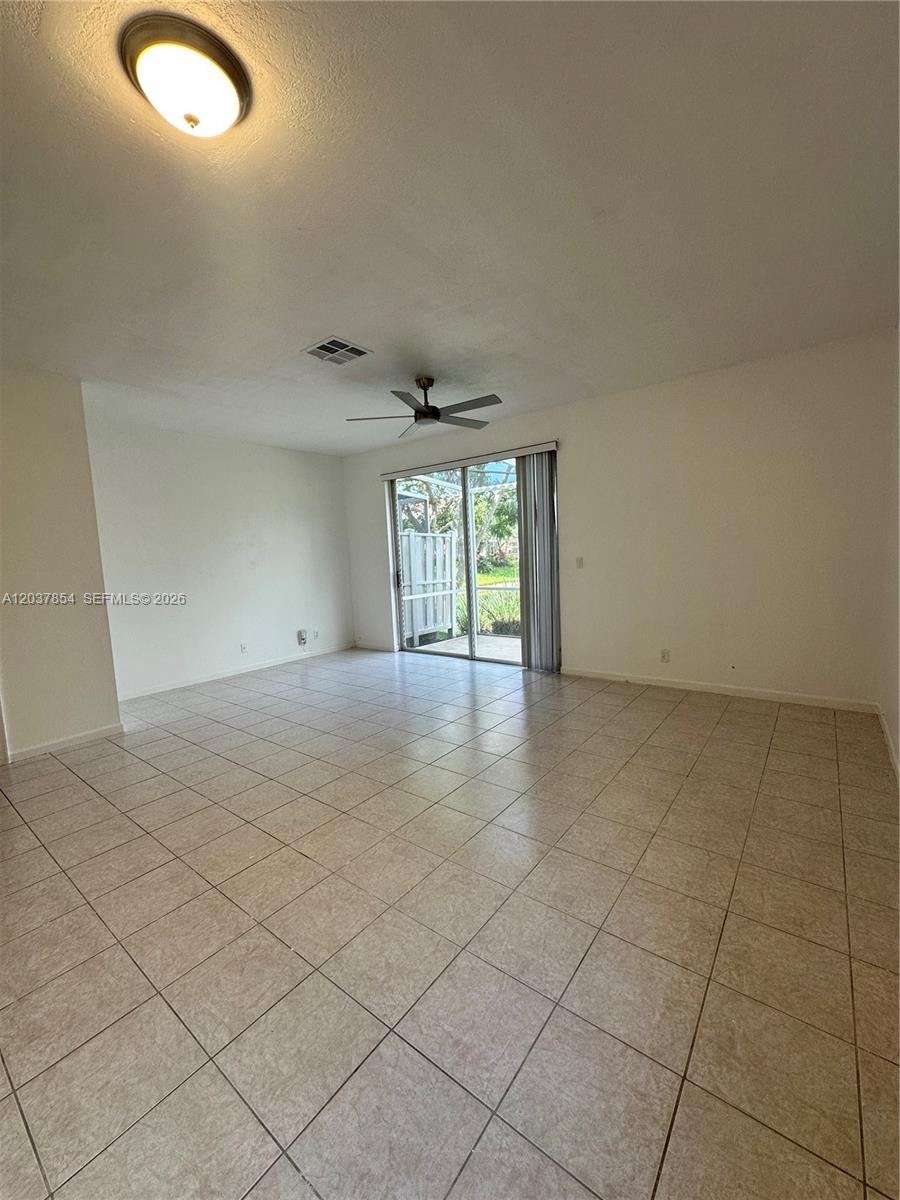 An empty living room features light-colored tile flooring, a ceiling fan, and sliding glass doors — 5541 NW 90th Ter # 5541, Sunrise FL 33351, SUNRISE, FL