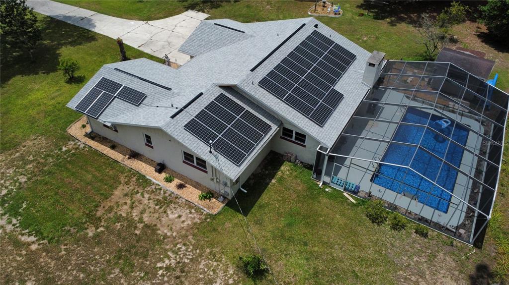 An aerial view of a house with solar panels on the roof and a screened-in pool — 8951 SW 202ND AVENUE ROAD, DUNNELLON, FL