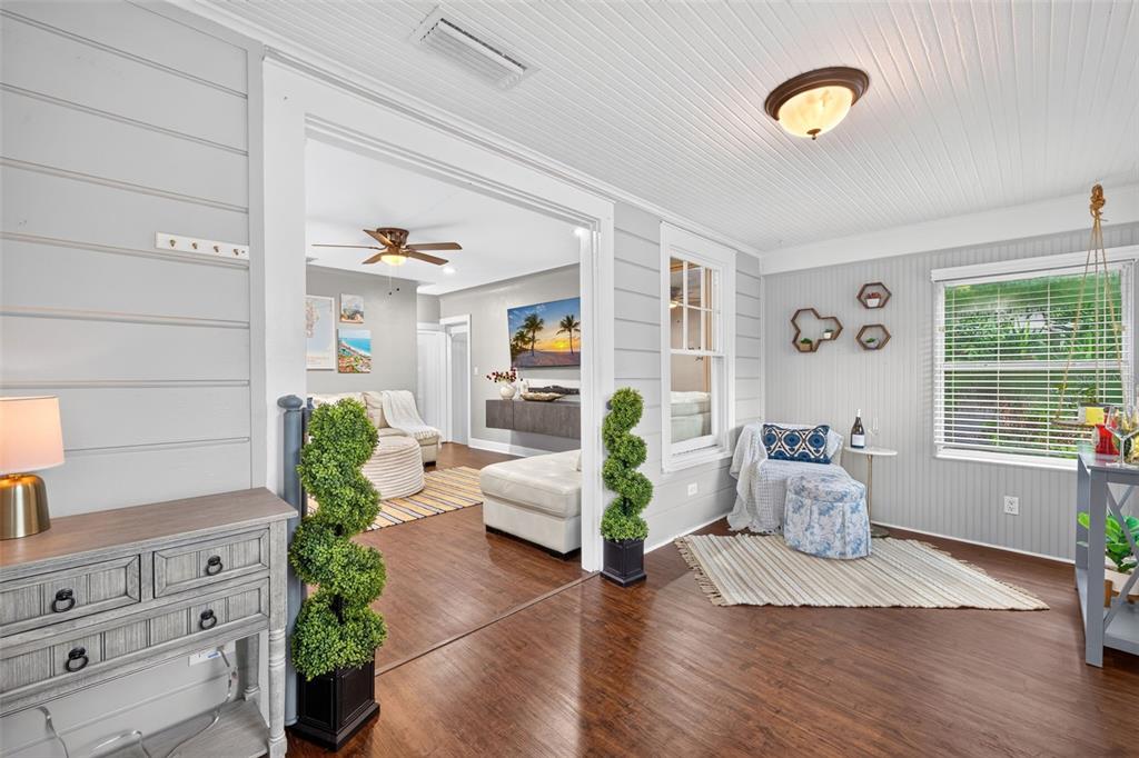 A living room and sunroom feature light gray walls, wood floors, and white beadboard ceilings — 920 29TH STREET N, ST PETERSBURG, FL