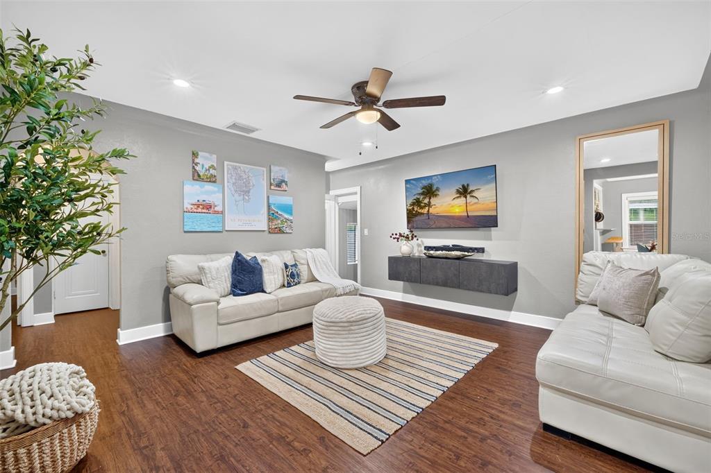 A living room features light gray walls, white leather sofas, a striped rug, and wood flooring — 920 29TH STREET N, ST PETERSBURG, FL
