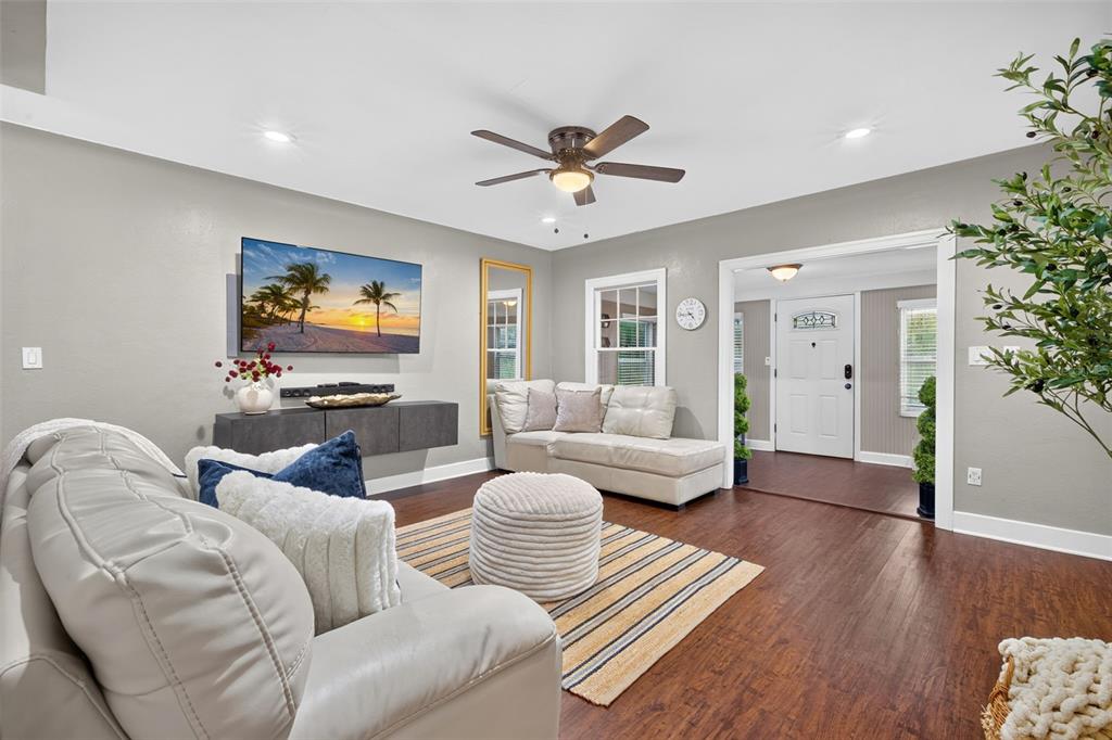 A living room features light gray walls, dark wood flooring, a ceiling fan, and white sofas — 920 29TH STREET N, ST PETERSBURG, FL
