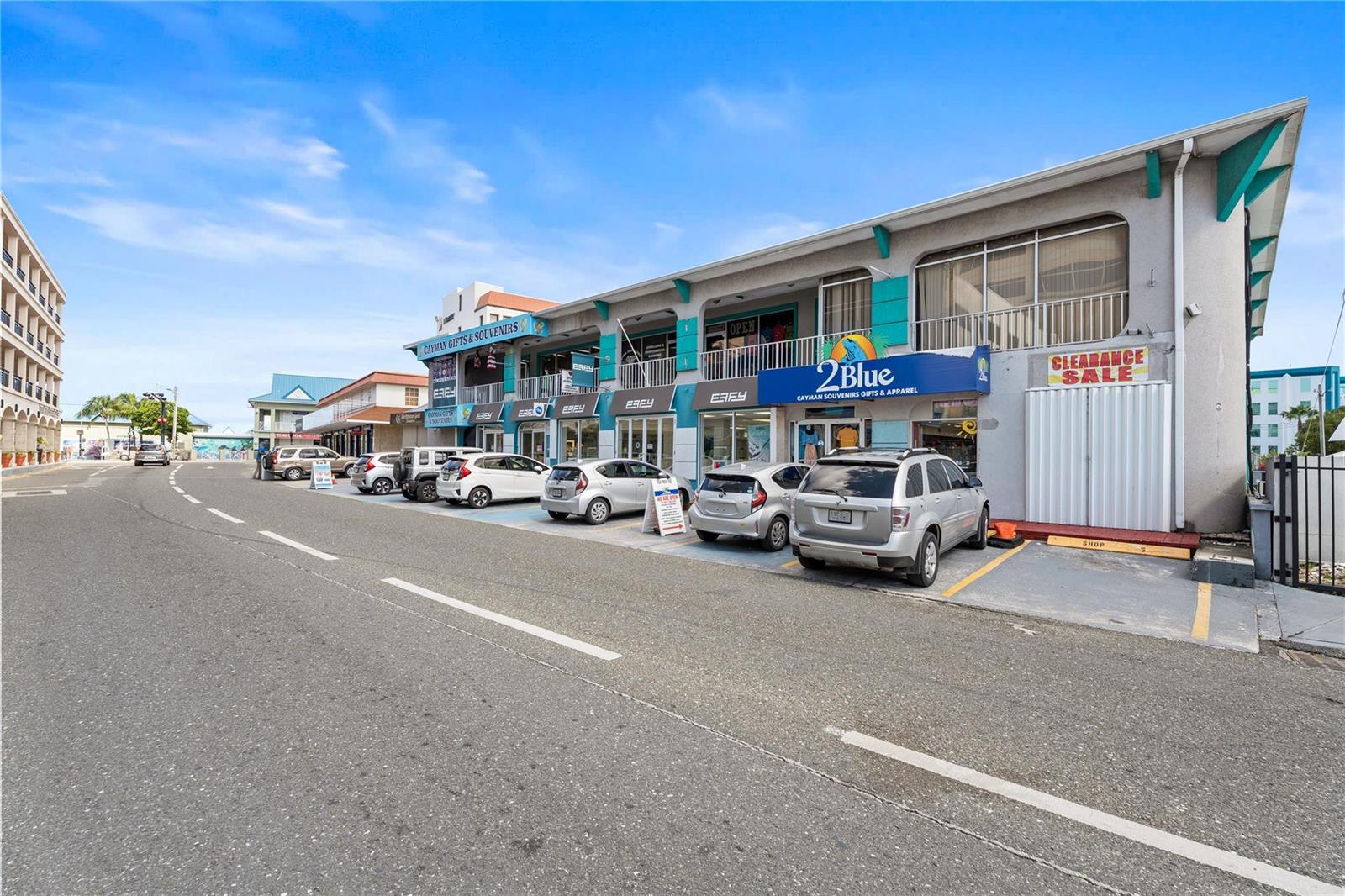 An exterior view of a multi-story commercial building with retail storefronts and parked cars — 19 Fort Street, GC, FL