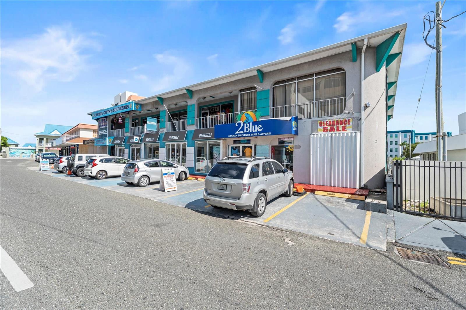 A two-story commercial building with retail storefronts and parked cars in front — 19 Fort Street, GC, FL