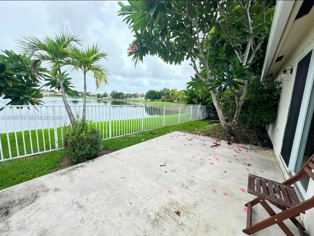 A concrete patio overlooks a lake behind a white metal fence with palm trees nearby — LAKE WORTH, FL