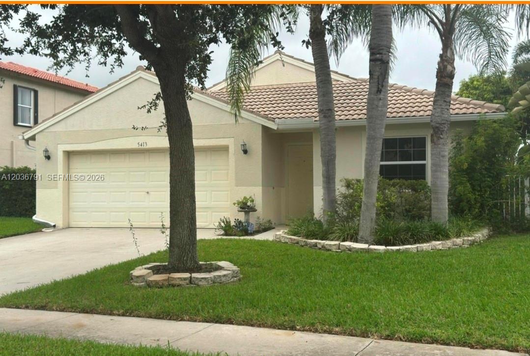 A single-story house with a two-car garage, tile roof, and palm trees in the front — LAKE WORTH, FL