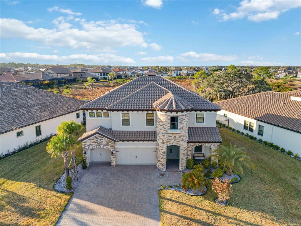 A two-story house with a stone turret, tile roof, and a paved driveway — 13845 HEARTWOOD WAY, PARRISH, FL