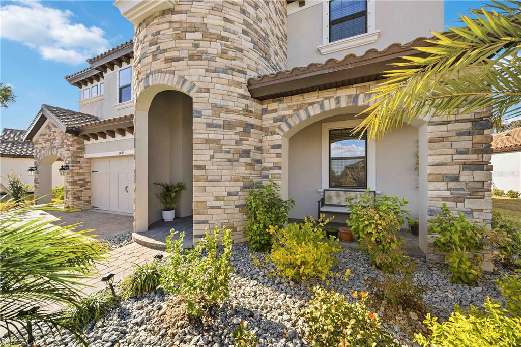 A stone-clad house exterior features a covered entryway, a garage, and a landscaped front yard — 13845 HEARTWOOD WAY, PARRISH, FL