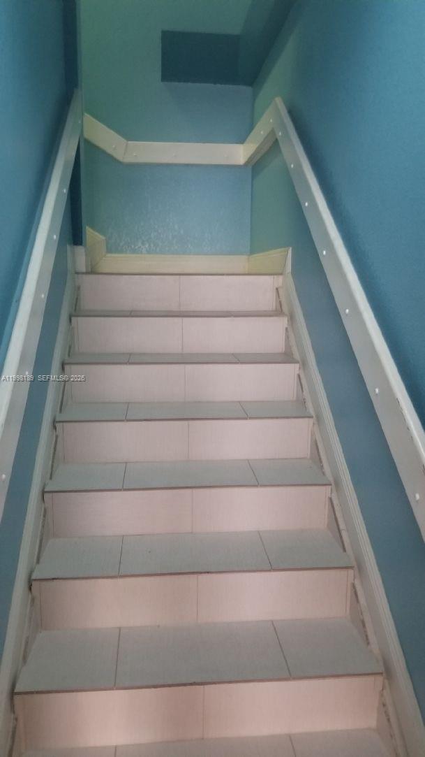A staircase with light-colored tiled steps leads upward between two blue walls — 1701 W 37th St # 15, Hialeah FL 33012, HIALEAH, FL