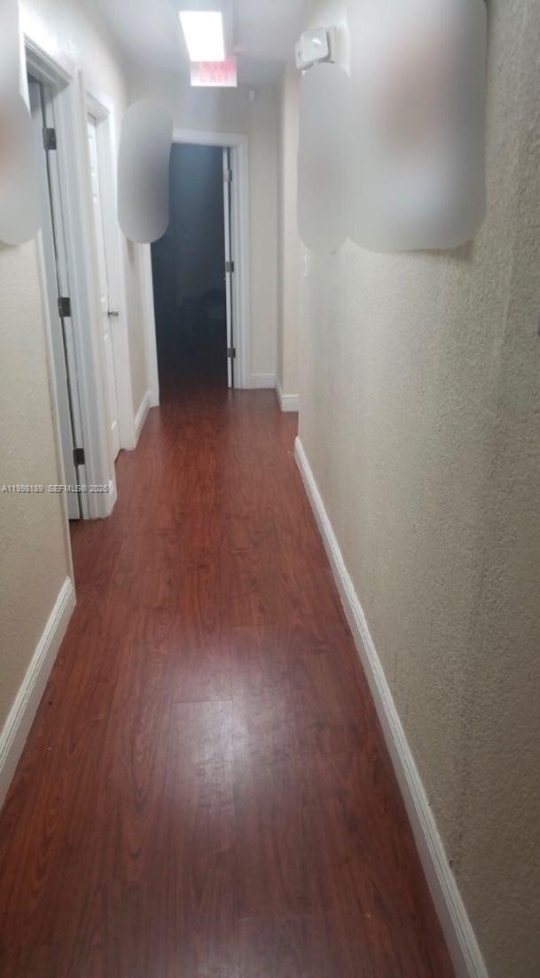 A narrow hallway features wood-look laminate flooring, white baseboards, and three closed interior doors — 1701 W 37th St # 15, Hialeah FL 33012, HIALEAH, FL