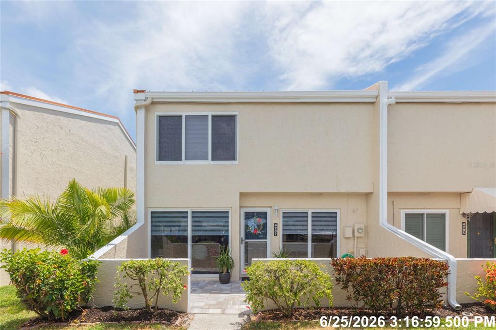 A two-story townhouse exterior features a paved front patio, small garden beds, and white siding — 4207 FOGCUTTER COURT, TAMPA, FL