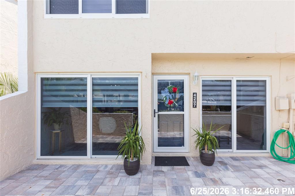 The exterior of a two-story home features a paved patio, sliding glass doors, and a front door — 4207 FOGCUTTER COURT, TAMPA, FL