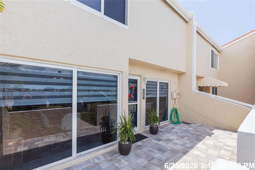 A paved patio area sits in front of a two-story building with sliding glass doors — 4207 FOGCUTTER COURT, TAMPA, FL