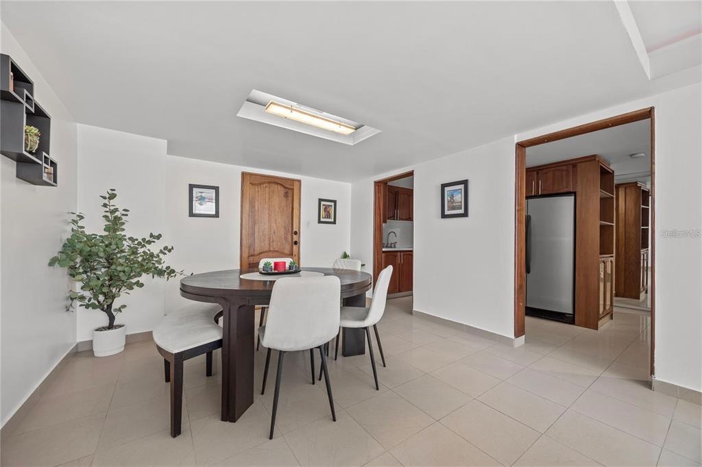 A dining room with a round table, white chairs, tile flooring, and an adjacent kitchen — 14 CALLE MARSEILLES UNIT 3D, SAN JUAN, PR