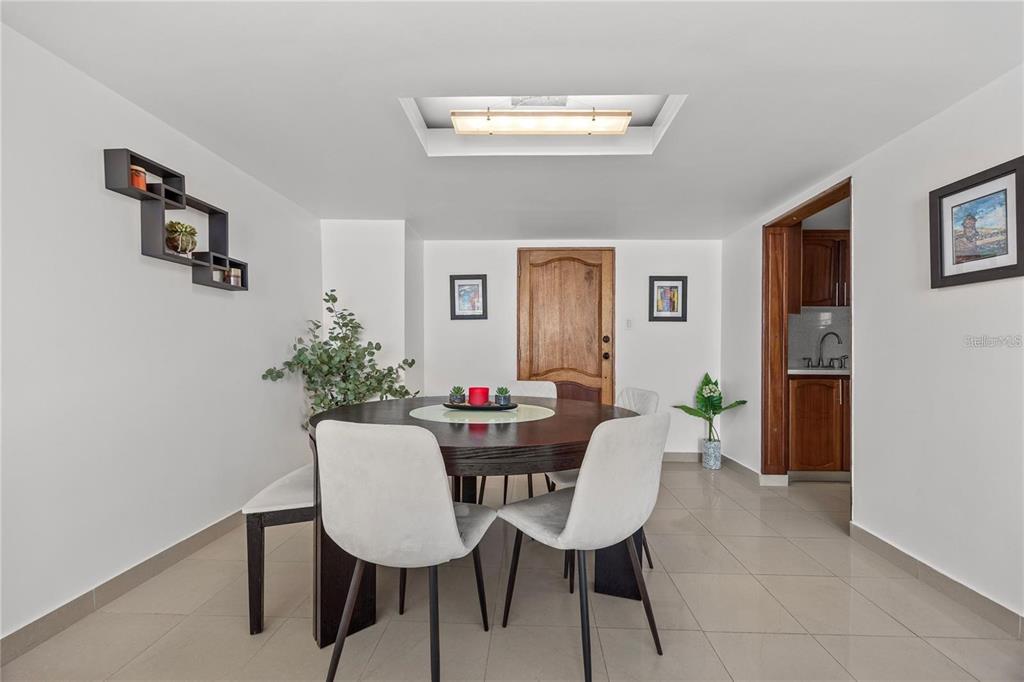 A dining room features a round wooden table, white chairs, a bench, and tile flooring — 14 CALLE MARSEILLES UNIT 3D, SAN JUAN, PR