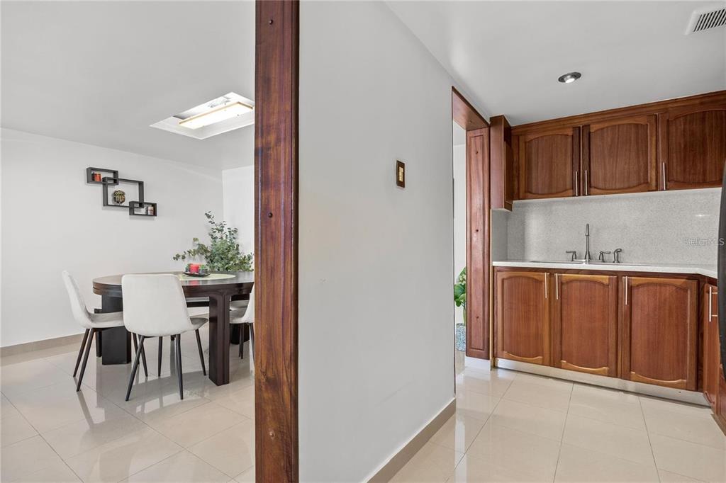A view from a hallway into a dining room and a kitchen with wood cabinets — 14 CALLE MARSEILLES UNIT 3D, SAN JUAN, PR