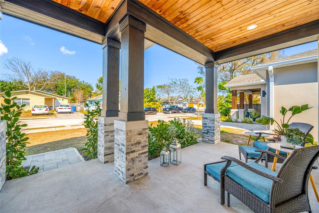 A covered porch features stone-based columns, a wood-paneled ceiling, and outdoor seating furniture — 2150 43RD TERRACE N, ST PETERSBURG, FL