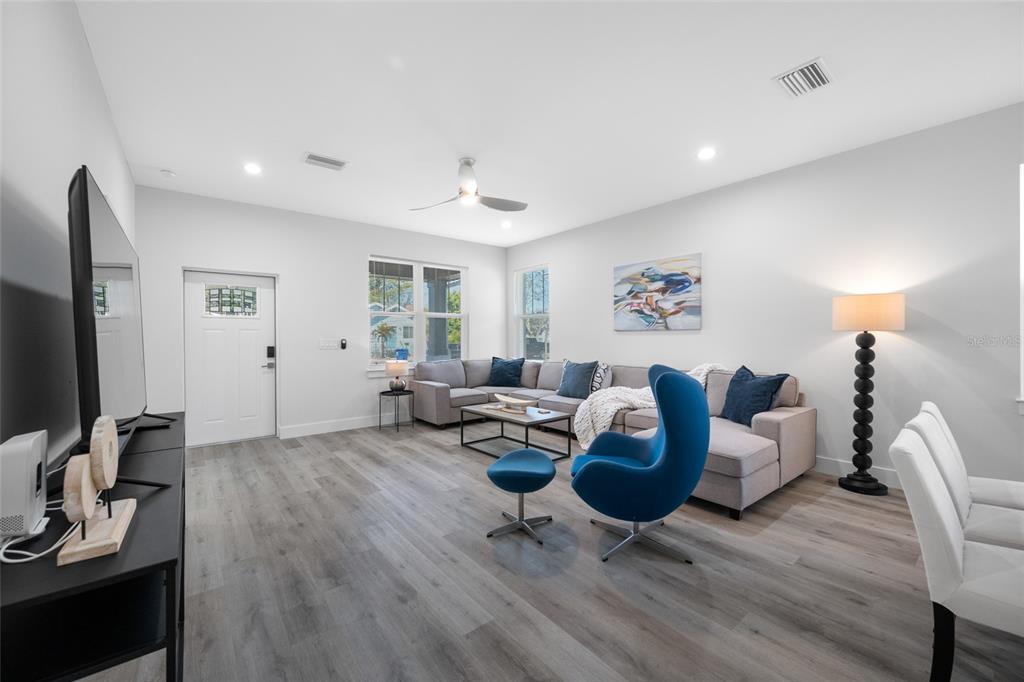 A living room features light wood-look flooring, a grey sectional sofa, and a blue accent chair — 2150 43RD TERRACE N, ST PETERSBURG, FL