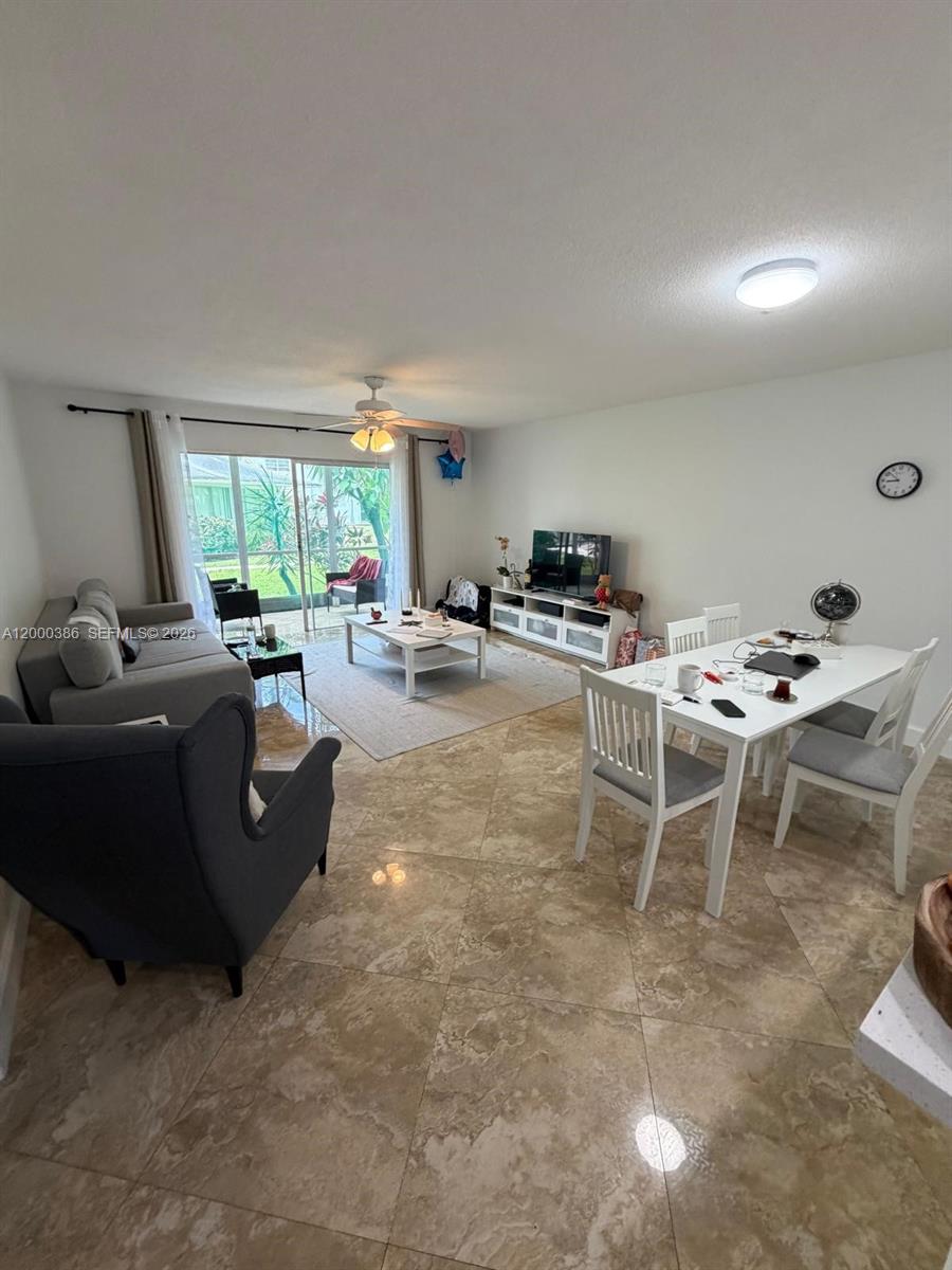A living and dining area features tile flooring, a sliding glass door, and white furniture — 219 NE 14th Ave # 101, Hallandale Beach FL 33009, HALLANDALE BEACH, FL