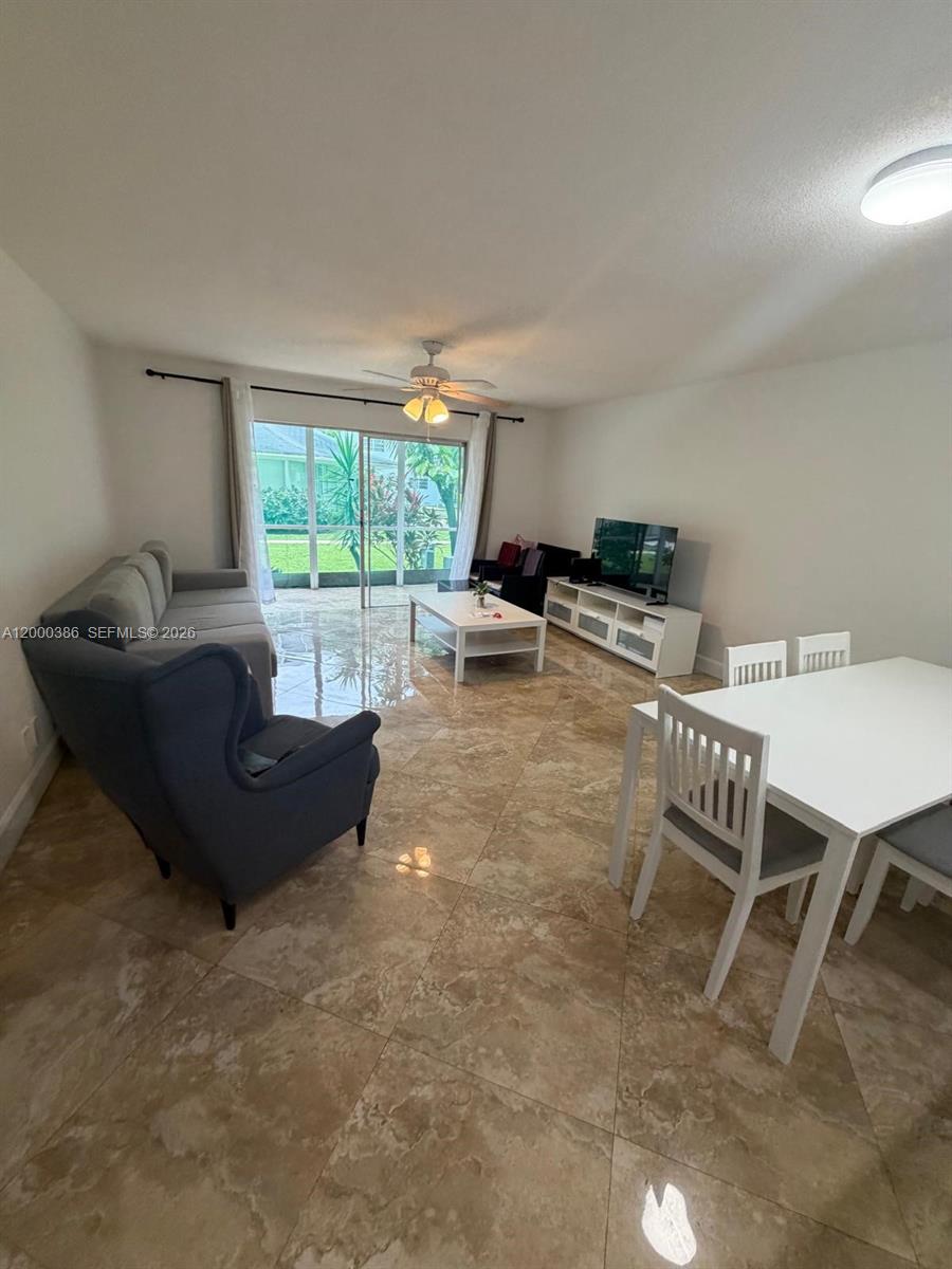 A living and dining area features tile flooring, a ceiling fan, and sliding glass doors — 219 NE 14th Ave # 101, Hallandale Beach FL 33009, HALLANDALE BEACH, FL