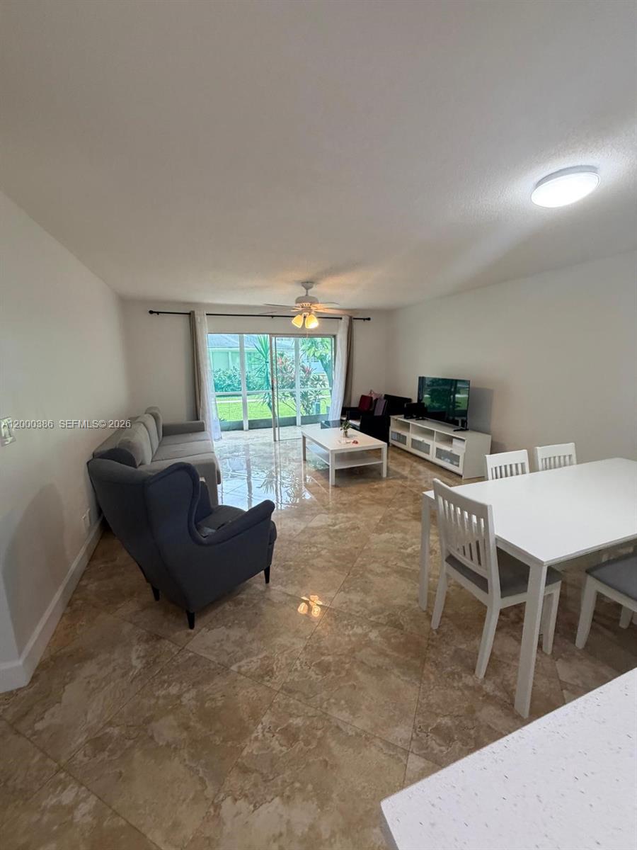 A living and dining area features tiled floors, a ceiling fan, and sliding glass doors — 219 NE 14th Ave # 101, Hallandale Beach FL 33009, HALLANDALE BEACH, FL